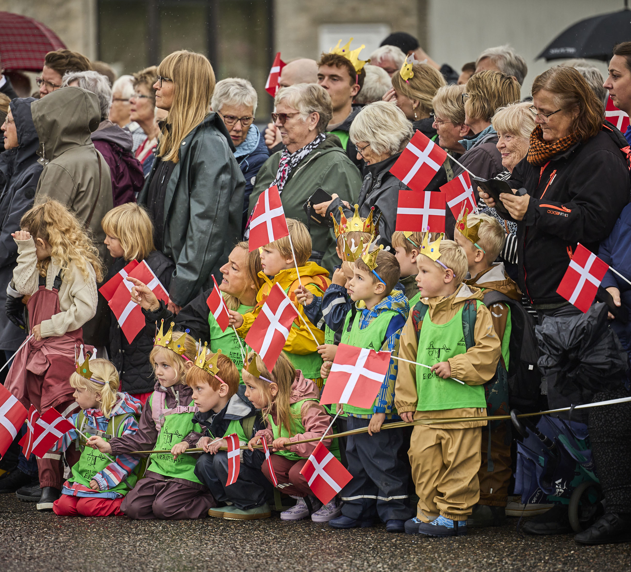 Folk står klar til at modtage Dronningen med flag på havnen